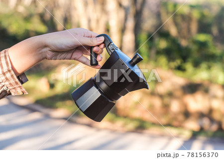 A hand holding a Moka Pot coffee machine. 78156370