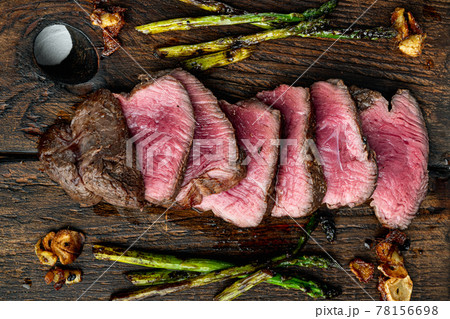 Sliced grilled marbled meat steak Filet Mignon, with onion and asparagus, on wooden serving board, top view flat lay 78156698
