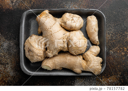 Ginger root , in plastic market container, on old dark rustic background, top view flat lay Ginger root , in plastic market container, on old dark rustic background, top view flat lay 78157782