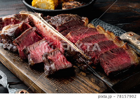 American cuisine. Sliced and roast T-bone or porterhouse beef medium rare meat Steak, on wooden serving board, on old dark wooden table background American cuisine. Sliced and roast T-bone or porterhouse beef medium rare meat Steak, on wooden serving board, on old dark wooden table background 78157902