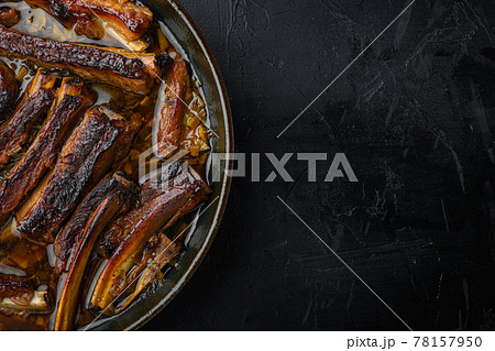 Barbecue pork spare ribs, in frying cast iron pan, on black stone background, top view flat lay, with copy space for text 78157950