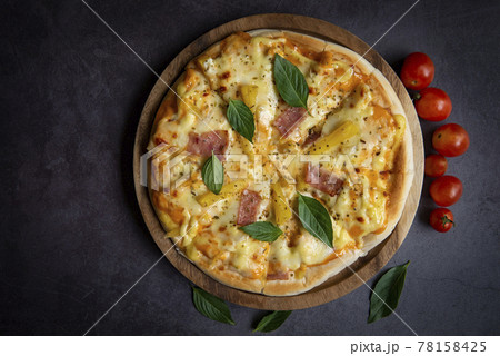 Tasty pizza homemade italian food style, pizza cheese ham and pineapple fruit cooking ingredients tomatoes basil on black background, Top view of pizza cheese italian food style. Flat lay Tasty pizza homemade italian food style, pizza cheese ham and pineapple fruit cooking ingredients tomatoes basil on black background, Top view of pizza cheese italian food style. Flat lay 78158425
