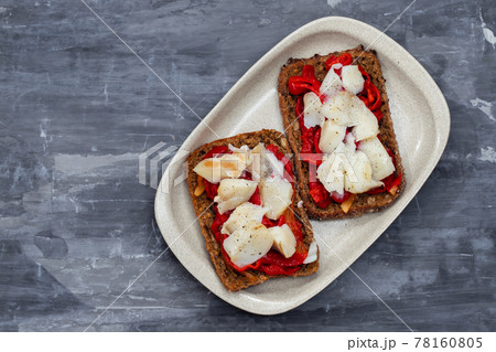 black healthy bread with cod fish and red pepper on dish 78160805