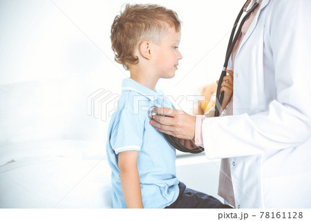 Happy smiling male kid-patient at usual medical inspection. Doctor and young boy in the clinic. Medicine concepts Happy smiling male kid-patient at usual medical inspection. Doctor and young boy in the clinic. Medicine concepts 78161128