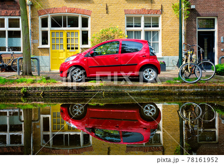 Red car on canal embankment in street of Delft. Delft, Netherlands Red car on canal embankment in street of Delft. Delft, Netherlands 78161952