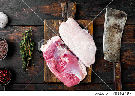Raw duck breast, on wooden cutting board with old butcher cleaver knife, on old dark wooden table background, top view flat lay 78162497