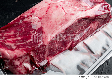 Vacuum black plastic pack with fresh beef steak cut, on black stone background Vacuum black plastic pack with fresh beef steak cut, on black stone background 78162580
