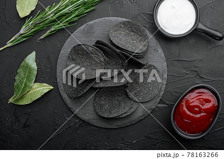 Cheese and chive potato crisp snack, on black stone background, top view flat lay 78163266