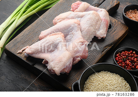 Uncooked chicken wings with spices, and sesame, on wooden cutting board, on old dark wooden table Uncooked chicken wings with spices, and sesame, on wooden cutting board, on old dark wooden table 78163286