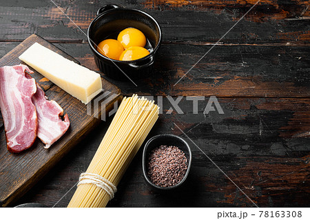 Ingredients for making pasta alla carbonara prosciutto, raw pasta, on old dark wooden table , with copy space for text 78163308