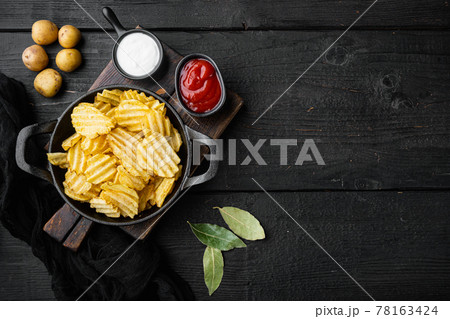 Home made potato chips, on black wooden background, top view flat lay, with copy space for text Home made potato chips, on black wooden background, top view flat lay, with copy space for text 78163424