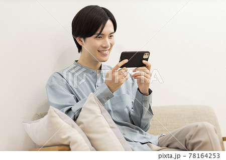 スマートフォンで動画を見る若い男性 78164253