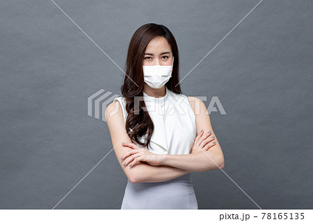 Young Asian woman in corporate wear with face mask crossing her arms Young Asian woman in corporate wear with face mask crossing her arms 78165135