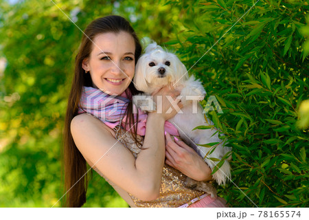 Young girl with her dog. Puppy white dog is running with it's owner. Concept about friendship, animal and freedom. Young girl with her dog. Puppy white dog is running with it's owner. Concept about friendship, animal and freedom. 78165574