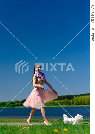 Young woman with her dog. Puppy white dog is running with it's owner. Concept about friendship, animal and freedom. Young woman with her dog. Puppy white dog is running with it's owner. Concept about friendship, animal and freedom. 78165575