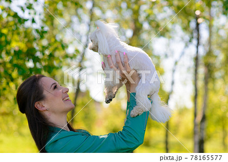 Young woman with her dog. Puppy white dog is running with it's owner. Concept about friendship, animal and freedom. 78165577