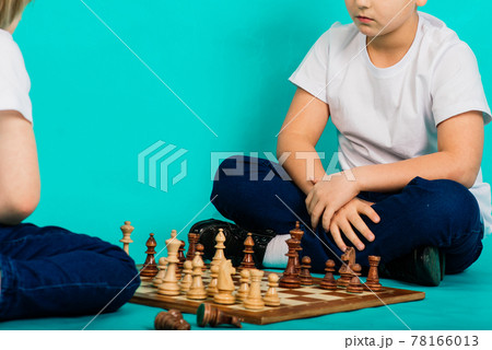 Two serious boy playing chess, studio, blue background 78166013