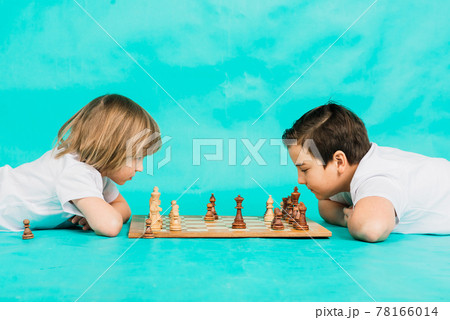 Two serious boy playing chess, studio, blue background 78166014