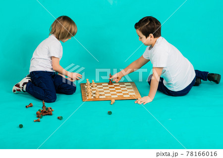 Two serious boy playing chess, studio, blue background 78166016