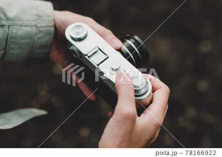 Female hands holding retro photo camera and adjust the sharpness. Toned. Noise 78166922