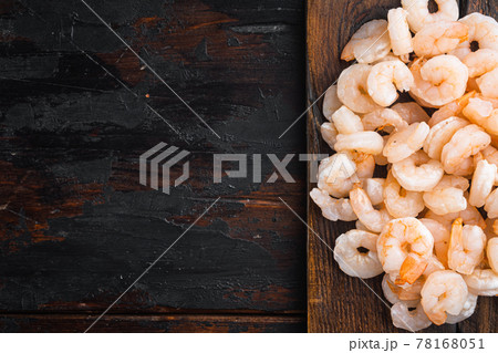 Pile of boiled peeled shrimps, on wooden serving board, on old dark wooden table , top view flat lay, with copy space for text Pile of boiled peeled shrimps, on wooden serving board, on old dark wooden table , top view flat lay, with copy space for text 78168051