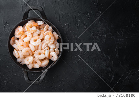 Shrimps - cooked and peeled, in frying cast iron pan or pot, on black stone background, top view flat lay, with copy space for text Shrimps - cooked and peeled, in frying cast iron pan or pot, on black stone background, top view flat lay, with copy space for text 78168180