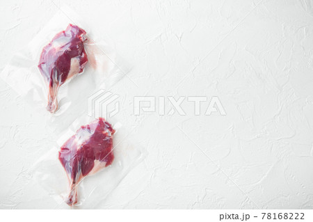 Vacuum packed raw duck leg, on white stone background, top view flat lay, with copyspace and space for text 78168222