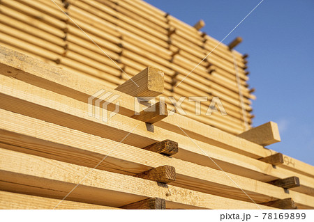 Storage of piles of wooden boards on the sawmill. Boards are stacked in a carpentry shop. Sawing drying and marketing of wood. Pine lumber for furniture production, construction. Lumber Industry. Storage of piles of wooden boards on the sawmill. Boards are stacked in a carpentry shop. Sawing drying and marketing of wood. Pine lumber for furniture production, construction. Lumber Industry. 78169899