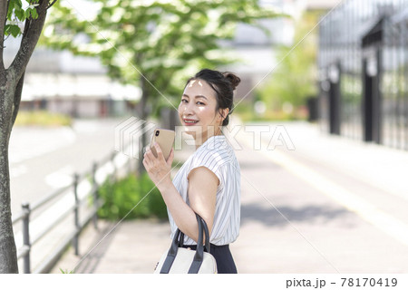 屋外でスマホを持つ女性 78170419