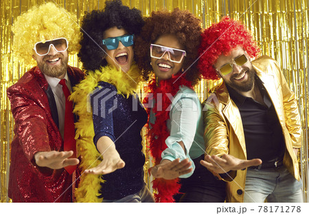 Happy young people in feather boas and curly wigs dancing and having fun at the club 78171278