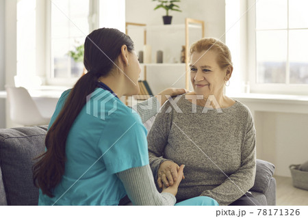 Friendly doctor and happy senior patient sitting on sofa, holding hands and talking Friendly doctor and happy senior patient sitting on sofa, holding hands and talking 78171326