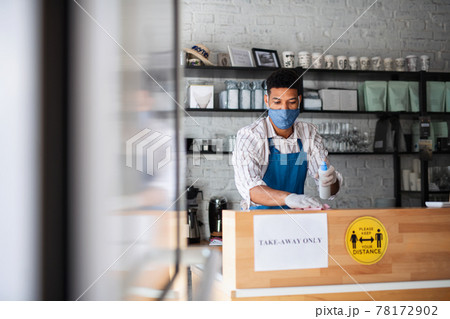 Waiter disinfecting surfaces in cafe, small business, coronavirus and new normal concept. Waiter disinfecting surfaces in cafe, small business, coronavirus and new normal concept. 78172902
