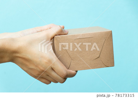 Woman hand hold the brown corrugated box on blue wall background with copy space Woman hand hold the brown corrugated box on blue wall background with copy space 78173315