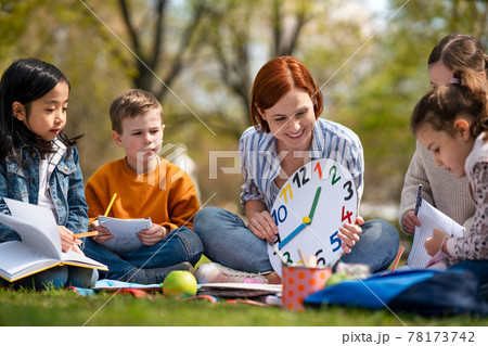 Teacher with small children sitting outdoors in city park, learning group education concept. 78173742