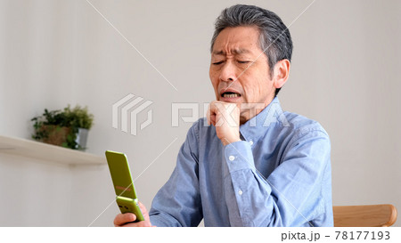 ガラケーの操作に困るシニア男性 78177193