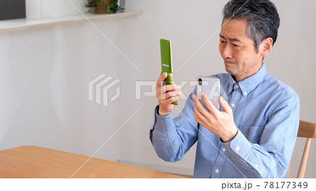 スマホとガラケーを比較するシニア男性 スマホとガラケーを比較するシニア男性 78177349