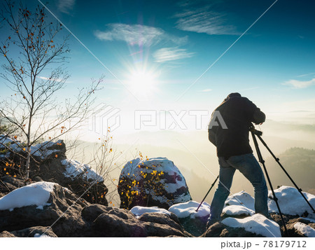 Nature photographer taking photos in the snowy mountains Nature photographer taking photos in the snowy mountains 78179712