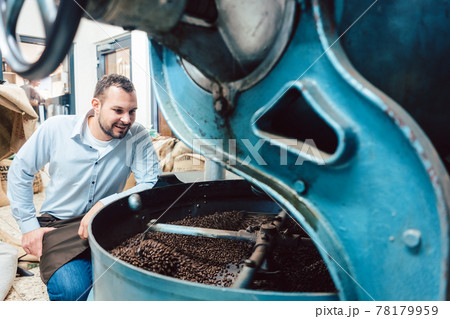 Man operating coffee roaster in factory 78179959