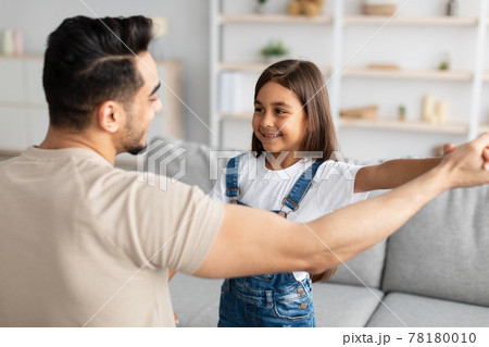 Dad and daughter dancing in living room together 78180010