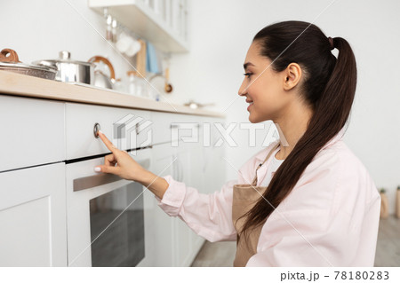 Woman using stove cooking food in kitchen Woman using stove cooking food in kitchen 78180283