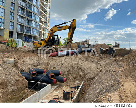 Powerful yellow industrial professional excavator doing earthwork underground repair work and burying large black water pipes at a construction site Powerful yellow industrial professional excavator doing earthwork underground repair work and burying large black water pipes at a construction site 78182735