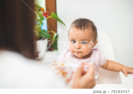 Mother feed her little daughter with a spoon Mother feed her little daughter with a spoon 78183437