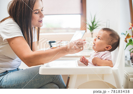 Mother feed her little daughter with a spoon Mother feed her little daughter with a spoon 78183438