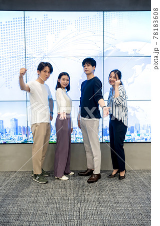 巨大モニターの前でポーズをとる若い男女 78183608