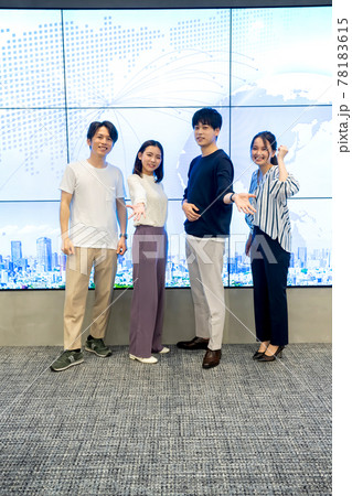 巨大モニターの前でポーズをとる若い男女 78183615