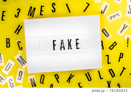 Lightbox text FAKE on yellow background with letters scattered, manipulation Lightbox text FAKE on yellow background with letters scattered, manipulation 78183832