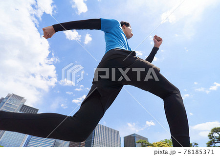 青空のもとでジョギングをする若い男性 78185371