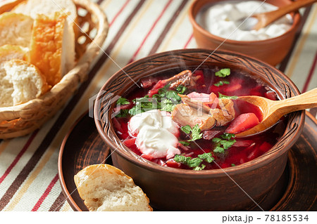 Freshly cooked hot homemade borscht - traditional dish of Russian and Ukrainian cuisine in earthenware dishes with bacon, bread, sour cream and garlic Freshly cooked hot homemade borscht - traditional dish of Russian and Ukrainian cuisine in earthenware dishes with bacon, bread, sour cream and garlic 78185534