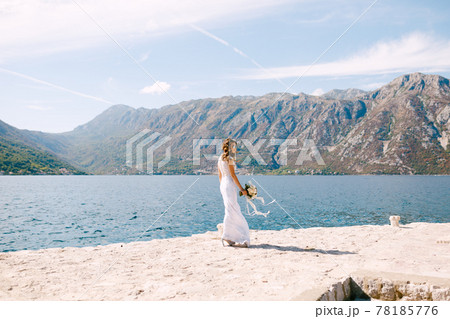 Lovely bride walks along the sunny coast with a beautiful wedding bouquet of flowers Lovely bride walks along the sunny coast with a beautiful wedding bouquet of flowers 78185776