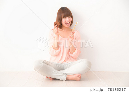 おやつと歯ブラシを手に胡座をかいて座る若い女性 78186217